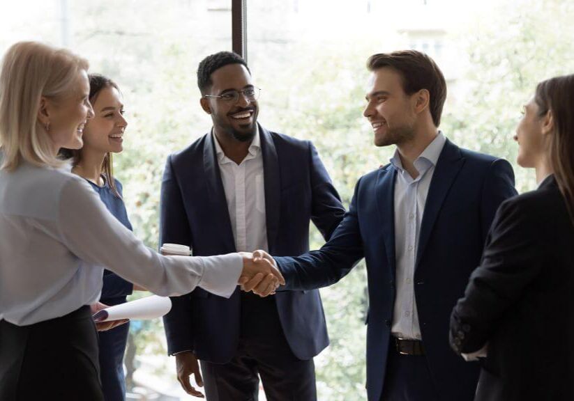 Smiling diverse businesspeople shake hands greeting getting acquainted at office meeting, happy colleagues employees handshake closing deal or making agreement after successful negotiations