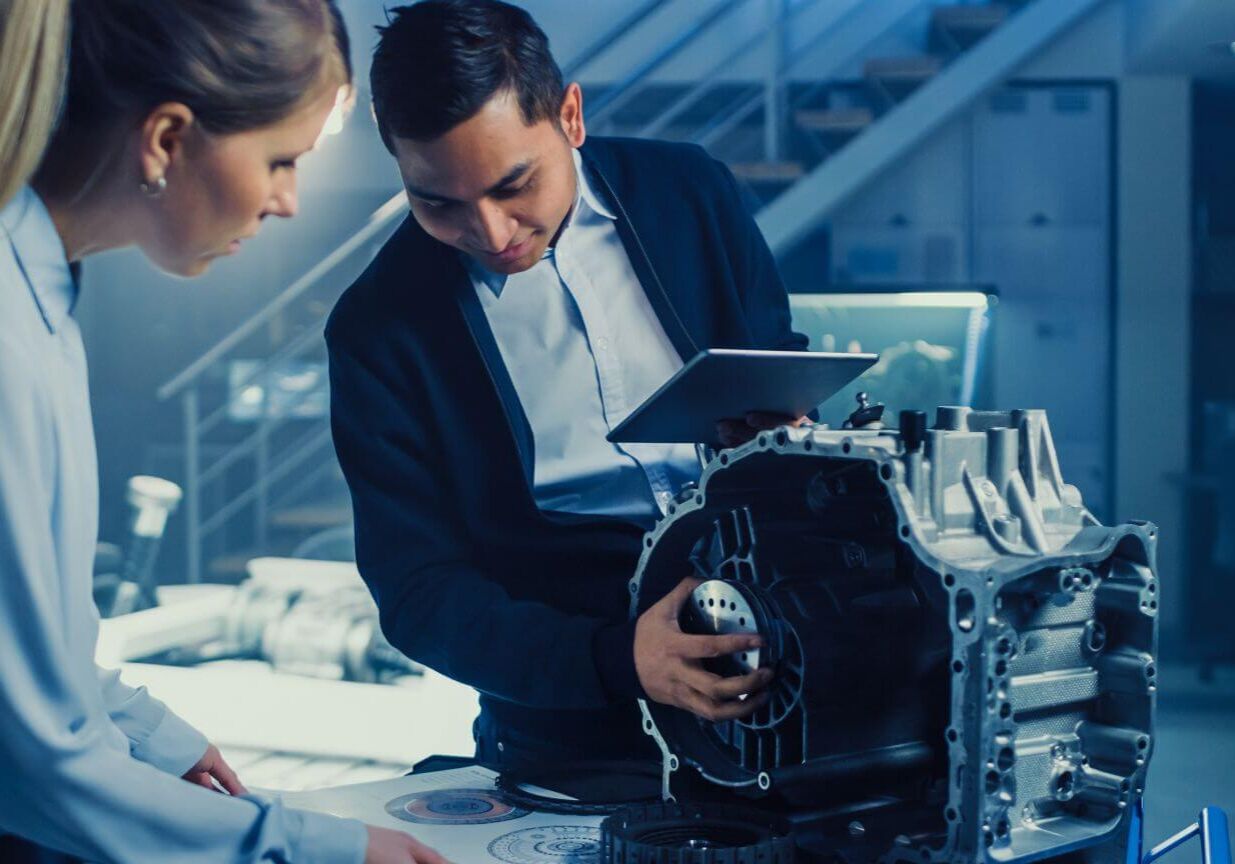 Development Laboratory Room with Professional Automotive Design Engineer Working on a Electric Car Gear Transmission. Chassis with Wheels, Batteries, Engine and Suspension.